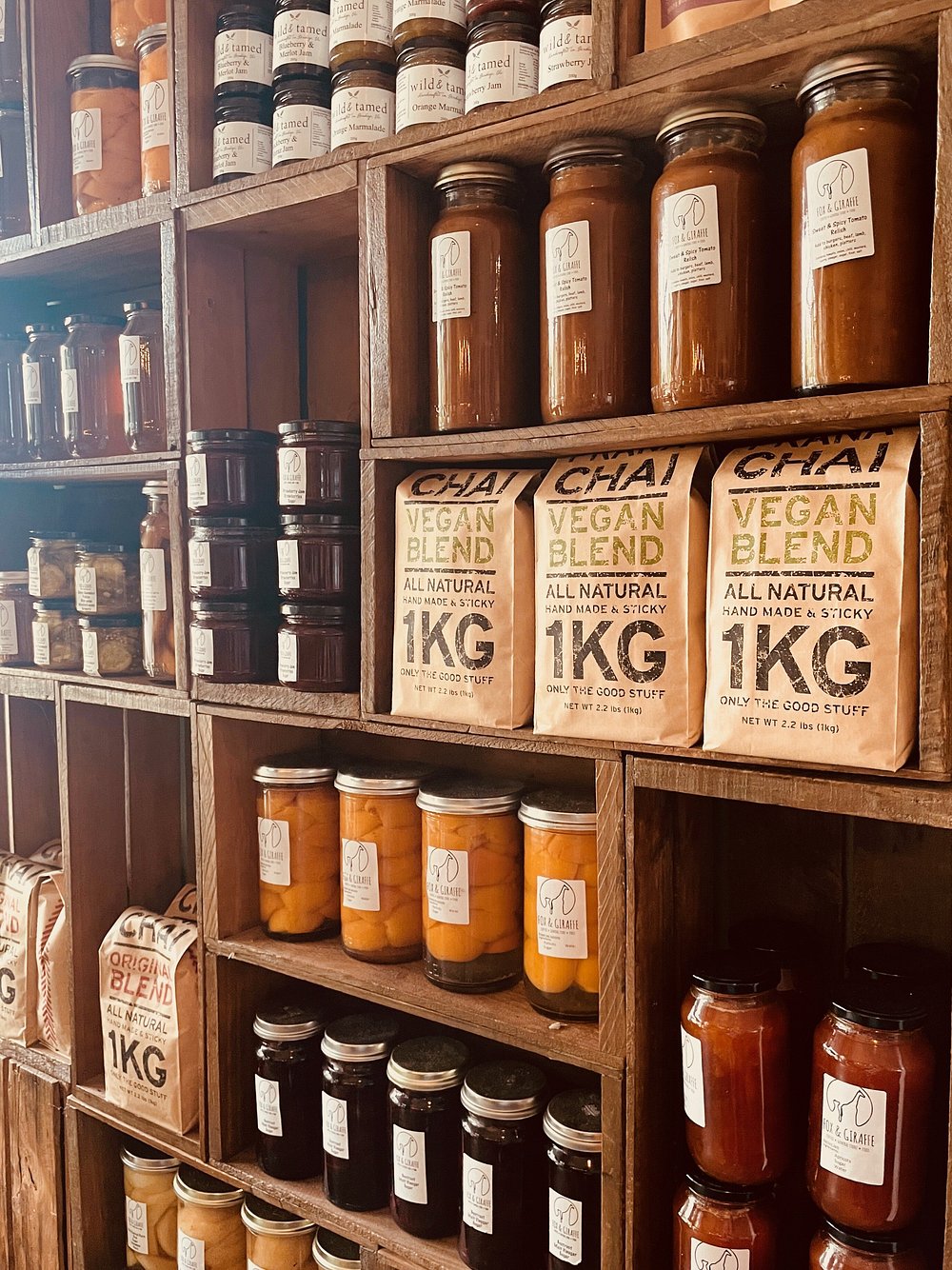 Wooden shelves with jars of various sizes and types, including 'Vegan Blend' bags.